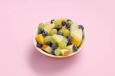 Pembe arka planda taze meyve salatası.