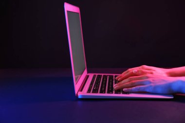 Siyah arka planda modern dizüstü bilgisayarla çalışan kadın