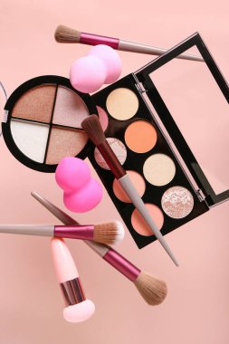 Pembe arka planda uçan makyaj malzemeleri ve kozmetik ürünleri, yakın plan.