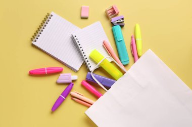 Kese kağıdıyla kompozisyon ve sarı arkaplanda farklı kırtasiye malzemesi