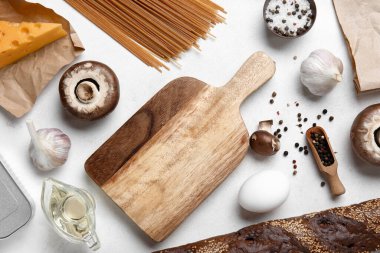 Wooden board with fresh products on grunge white kitchen table clipart