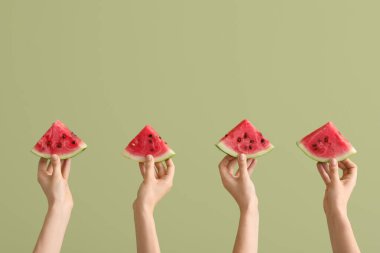 Yeşil arka planda olgun karpuz dilimleriyle kadın elleri.