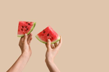 Bej arka planda olgun karpuz dilimleriyle kadın elleri