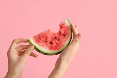 Pembe arka planda olgun karpuz dilimli kadın elleri