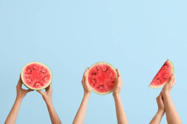 Yarım yamalak kadın elleri ve mavi arka planda olgun karpuz dilimleri.