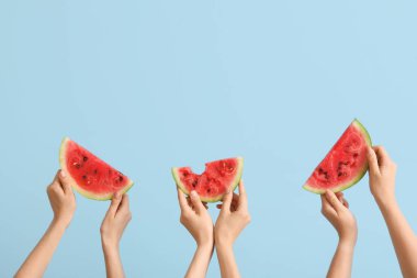 Mavi arka planda olgun karpuz dilimleriyle kadın elleri