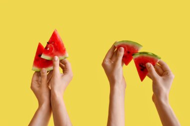 Sarı arka planda olgun karpuz dilimleriyle kadın elleri.