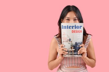 Pembe arka planda dergisi olan düşünceli, güzel, Asyalı bir kadın.