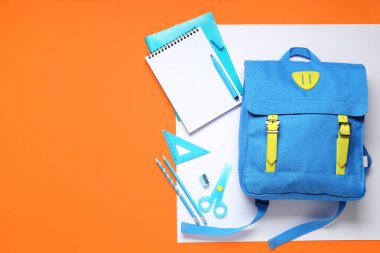 Renk arkaplanı üzerinde farklı kırtasiye malzemesi olan şık okul çantası