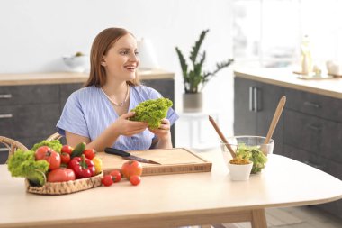 Mutfaktaki masada sebze salatası yapan genç kadın.