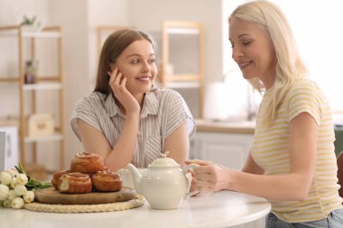 Kızıyla birlikte mutfakta çay içen olgun bir kadın. Anneler Günü kutlaması