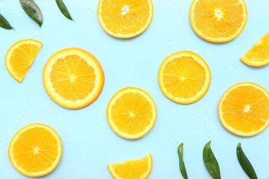 Yapraklı portakal dilimleri ve mavi arkaplanda su damlaları