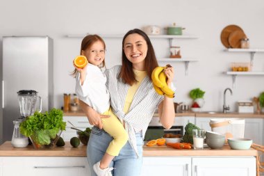 Annesiyle küçük bir kız ve mutfakta sağlıklı meyveler.