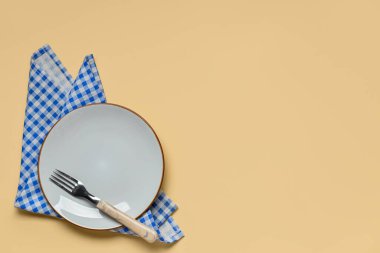 Boş tabak, çatal ve bej arka planda mavi kareli peçete