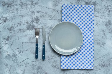 Masa ayarları mavi kareli masa örtüsü, boş tabak ve çatal bıçak.