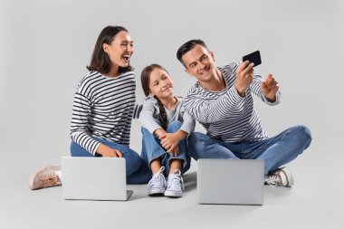 Gri arkaplanda selfie çeken mutlu bir aile.