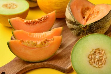 Sarı arka planda lezzetli olgun kavunları olan ahşap tahta.