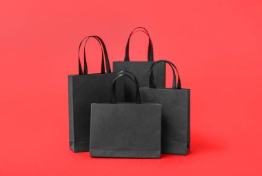 Kırmızı arka planda alışveriş torbaları. Kara Cuma konsepti