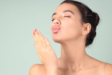 Güzel dudakları olan genç bir kadın yeşil arka planda öpüşüyor.