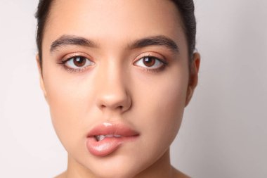 Açık arkaplanda güzel dudakları olan genç bir kadın, yakın plan.