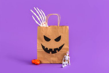 Leylak arka planında Cadılar Bayramı süsleri olan bir alışveriş çantası.