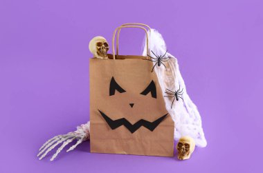 Leylak arka planında Cadılar Bayramı süsleri olan bir alışveriş çantası.