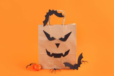 Turuncu arka planda Cadılar Bayramı süslemeleri olan bir alışveriş çantası.