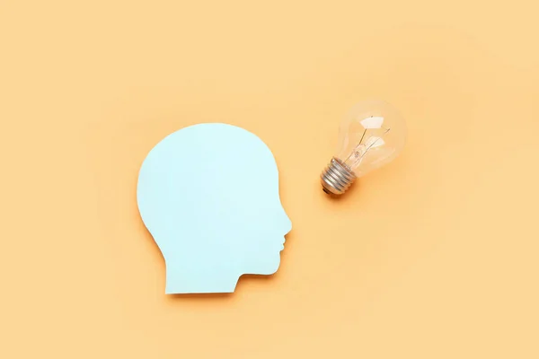 Paper human head with light bulb on color background. Logic concept