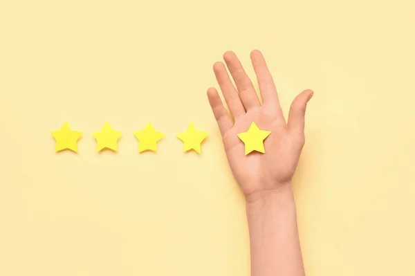 Female hand and five stars on color background. Customer experience concept