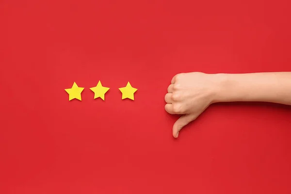Woman showing thumb-down and three stars on red background. Customer experience concept