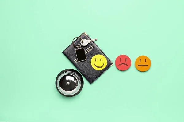 Rating smiles with passport, key from hotel room and service bell on turquoise background. Customer experience concept