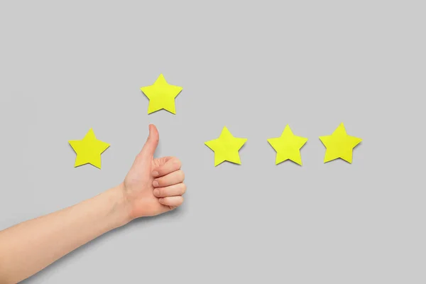 Woman showing thumb-up and five stars on light background. Customer experience concept