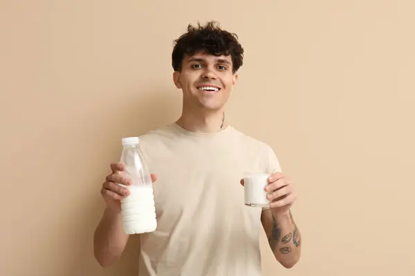 带着玻璃杯和米色背景牛奶的年轻人 — 图库照片