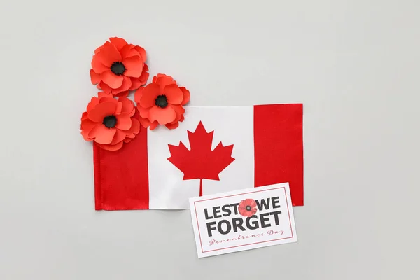 Poppy flowers, flag of Canada and card on grey background. Remembrance Day