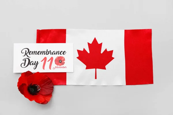Poppy flower, flag of Canada and card on grey background. Remembrance Day