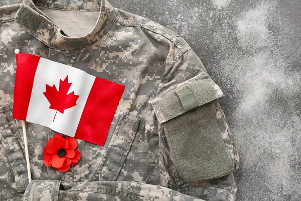 Poppy flower, flag of Canada and military uniform on grunge grey. Remembrance Day