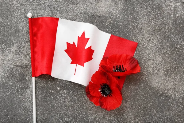 Poppy flowers and flag of Canada on grunge grey background. Remembrance Day