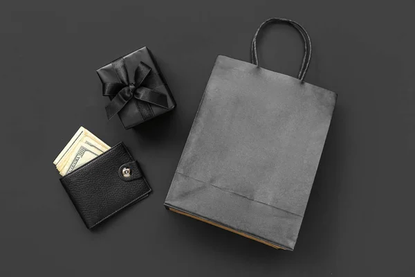 Shopping bag, gift box and wallet with money on black background. Black Friday concept