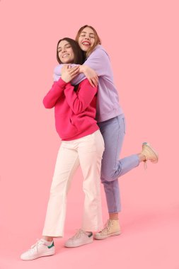 Pembe arka planda sarılan kız arkadaşlar