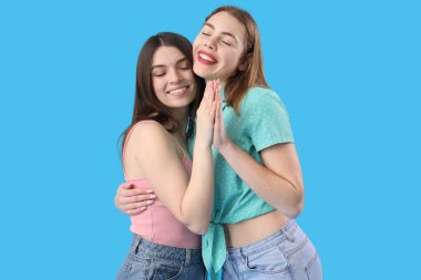 Mavi arka planda sarılan kız arkadaşlar