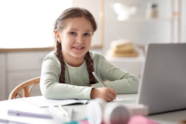 Bilgisayarlı küçük kız mutfakta bilgisayar bilimleri okuyor.