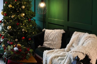 Oturma odasında Noel ağacı, kanepe ve çelenk sehpanın üzerinde.