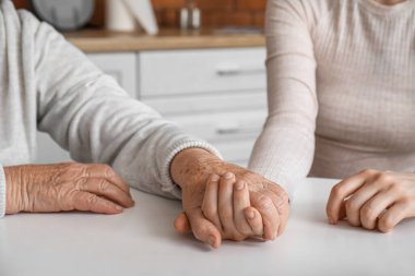 Mutfakta büyükannesiyle el ele tutuşan genç kadın, yakın plan.