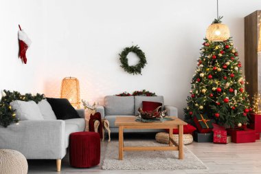 Oturma odasının içinde Noel ağacı, kanepeler ve kahve masası var.