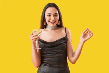 Sarı arka planda martinisi olan güzel bir kadın.