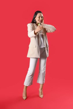 Kırmızı arka planda martinisi olan güzel bir kadın.