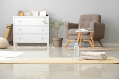 Oturma odasındaki jimnastik paspasının üstünde bir şişe su ve havluyla cep telefonu.