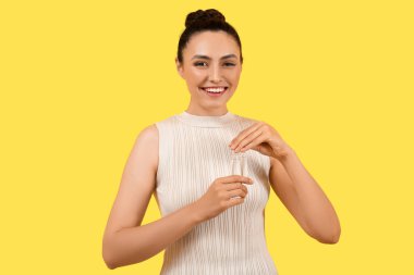 Sarı arka planda ampulleri olan güzel bir genç kadın.