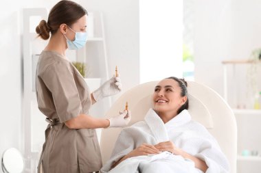 Güzellik salonunda ampulleri olan güzel bir kadın ve kozmetik uzmanı.