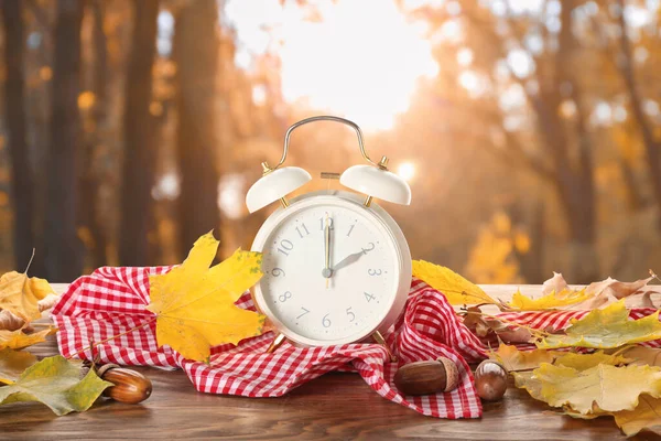 屋外のテーブルの上に目覚まし時計と秋の葉 昼間の節約時間終了 — ストック写真